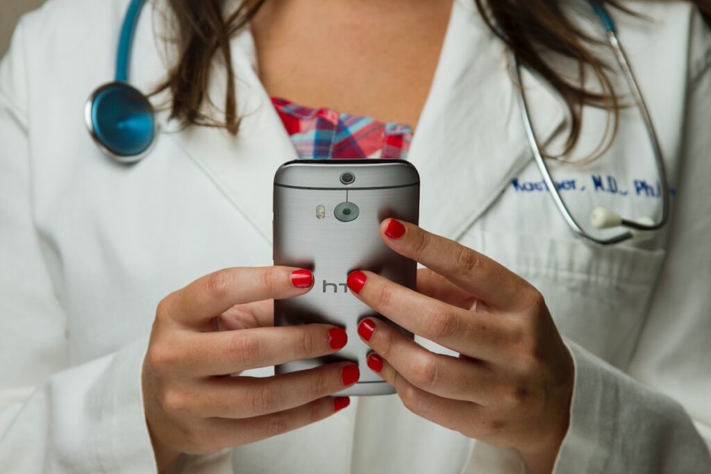 Doctor working on EMR using a gray HTC Android smartphone