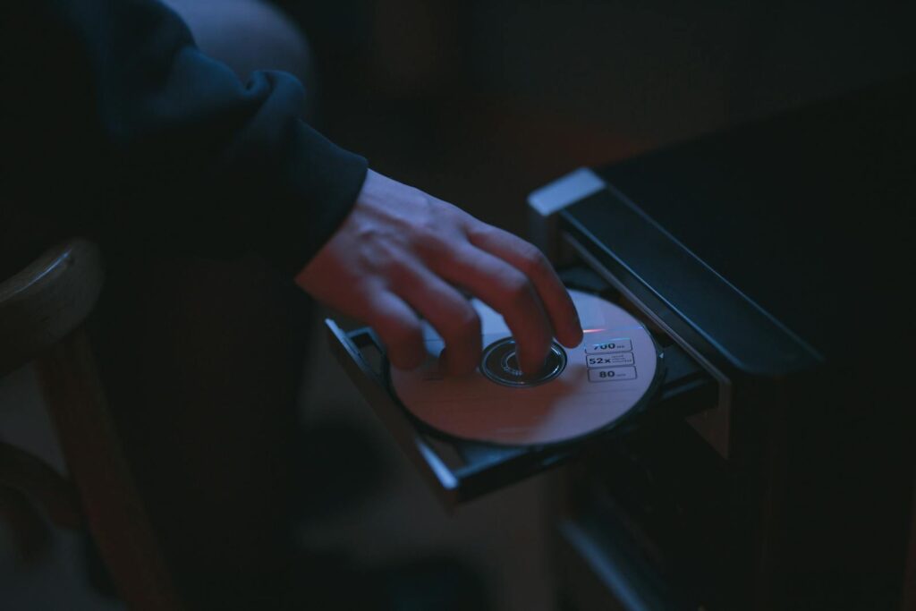 A hand inserting a CD into a computer drive, highlighting cyber security themes.
