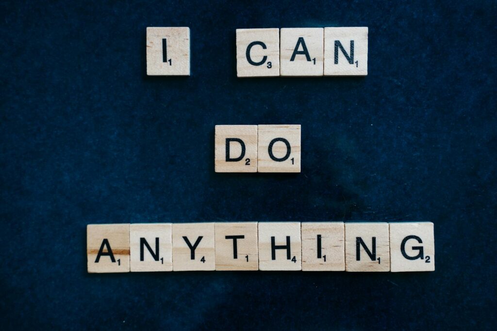 Inspirational phrase 'I Can Do Anything' created with Scrabble tiles on a blue surface.