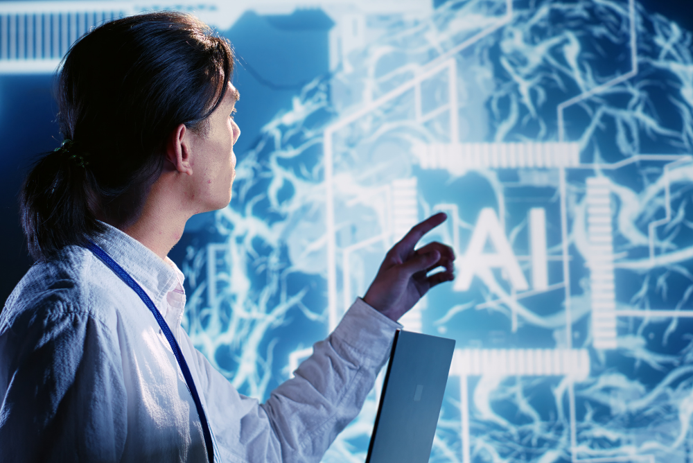 A person in a white shirt uses a laptop, pointing at a glowing blue interface with "AI" highlighted. The scene conveys a futuristic technology theme.