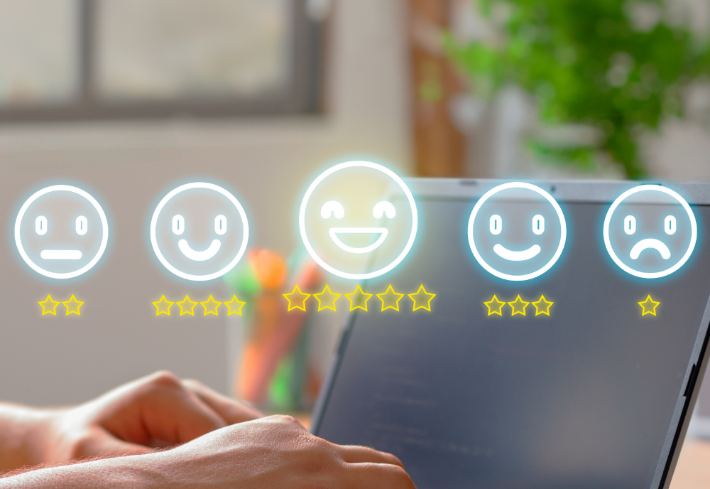 User interacts with a laptop displaying a feedback rating system with five emoticons ranging from sad to happy, with star ratings below each. Bright, positive mood.