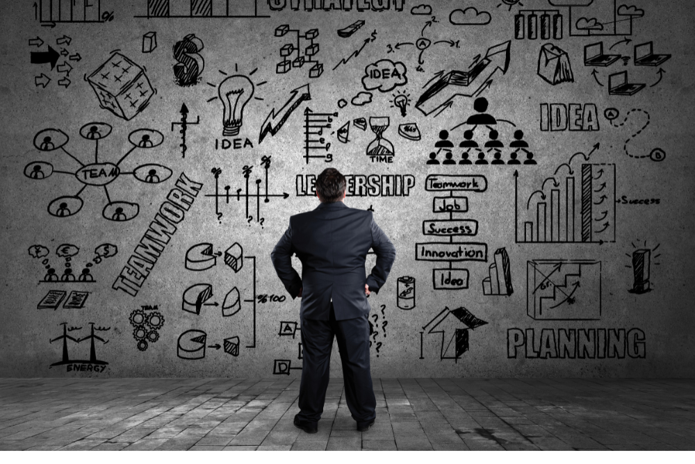 Businessman in formal attire stands before a wall covered in colorful doodles, showcasing creativity and innovation.